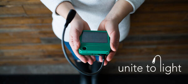 Unite to Light logo on a background image of a woman holding a solar powered light Unite to Light logo on a background image of a woman holding a solar powered light