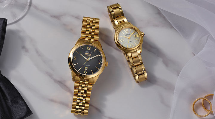 Wedding & Engagement Watch Gifts; Image of men's and women's watches sitting on a table with wedding rings, a tie and champagne glass. Featuring Rolan watch model AW0152-58H and Ceci watch model EM1162-52A